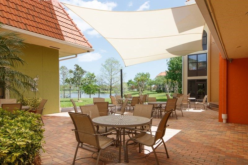A scenic outdoor patio featuring tables and chairs with a shade sail overhead.