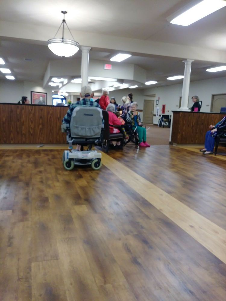 A waiting area with people and a wheelchair on a wooden floor.