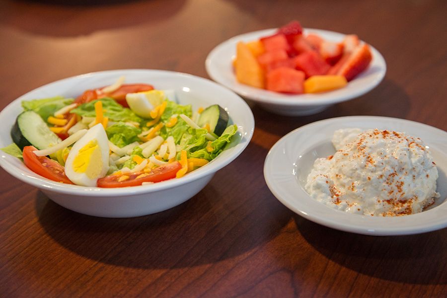 A colorful spread of a fresh salad, mixed fruit, and a creamy dip.