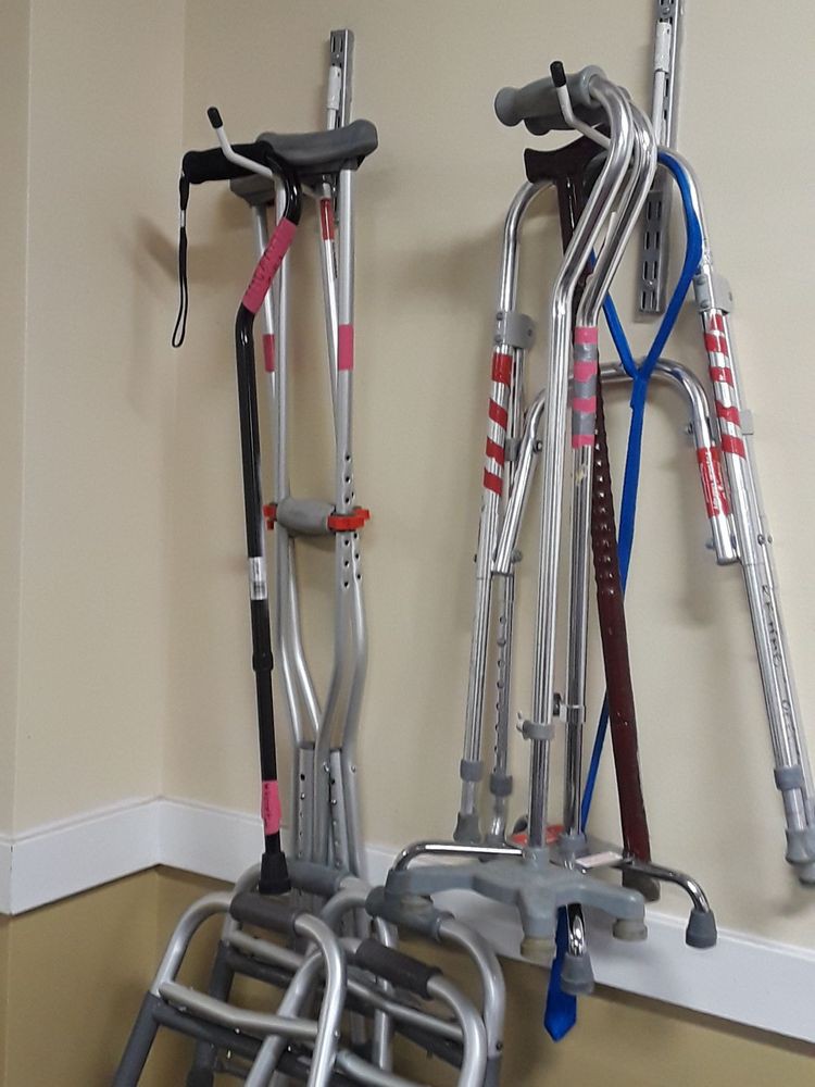 A collection of crutches and walkers organized against a wall.