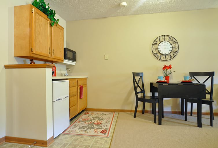 A cozy kitchen and dining area with wooden cabinets, a dining table, and wall decor.