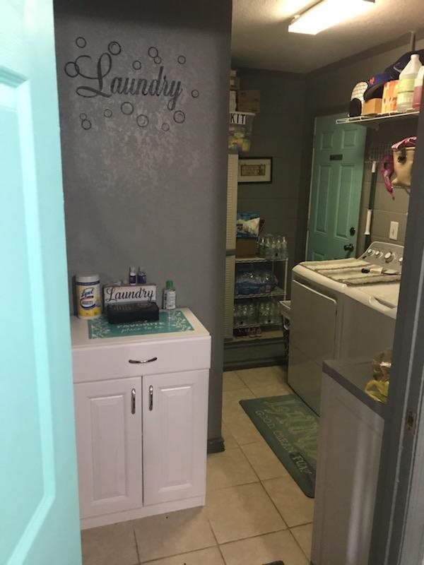 A cozy laundry room with a washer and dryer set, storage cabinet, and decorative accents.
