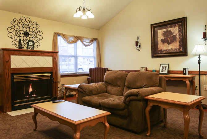 A cozy living room with a brown couch, coffee tables, and a fireplace.