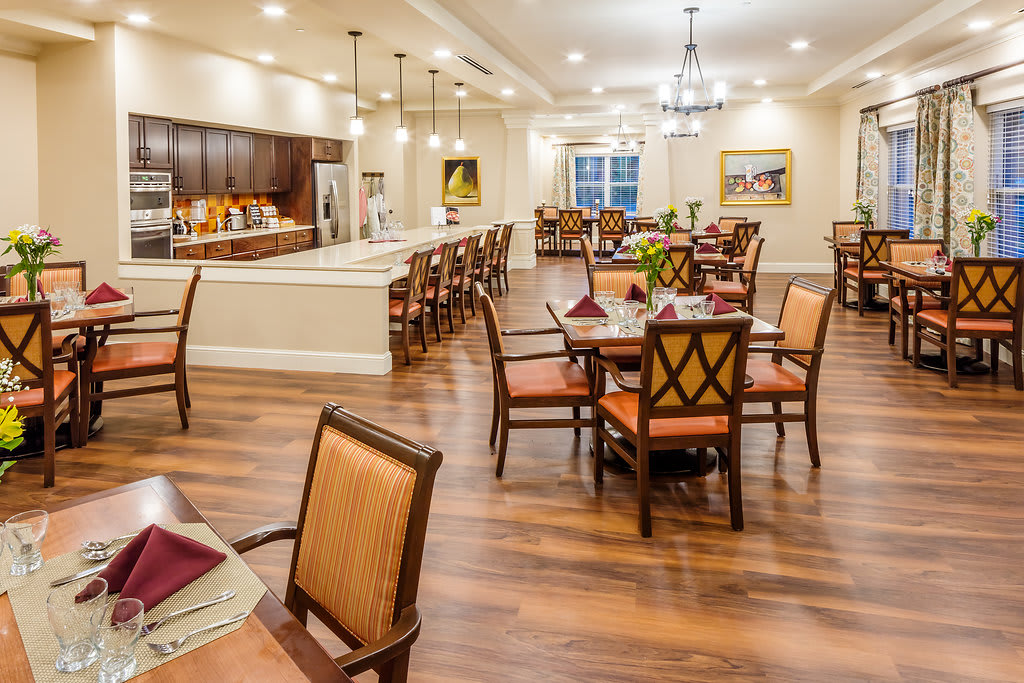 A beautifully designed dining area with neatly arranged tables and chairs, warm lighting, and a modern interior.