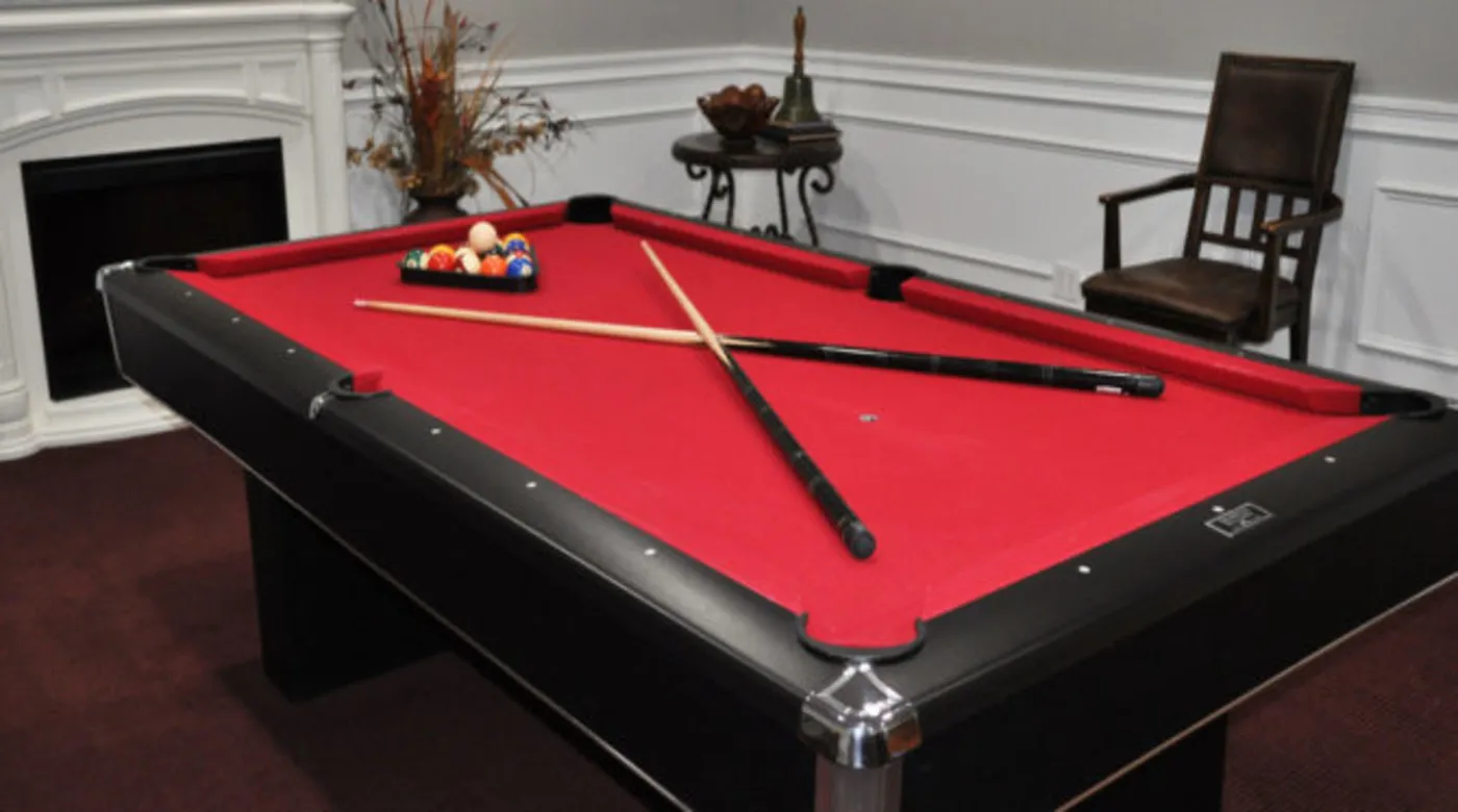 A stylish pool table with red felt and cue sticks arranged on top.