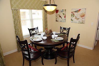 A cozy dining room setting with a round wooden table and four chairs, complete with elegant place settings and ambient lighting.