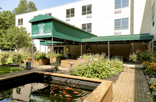 A serene outdoor dining area featuring a pond and lush greenery.