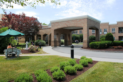 A welcoming entrance to a well-maintained building, surrounded by lush gardens and a clear blue sky.