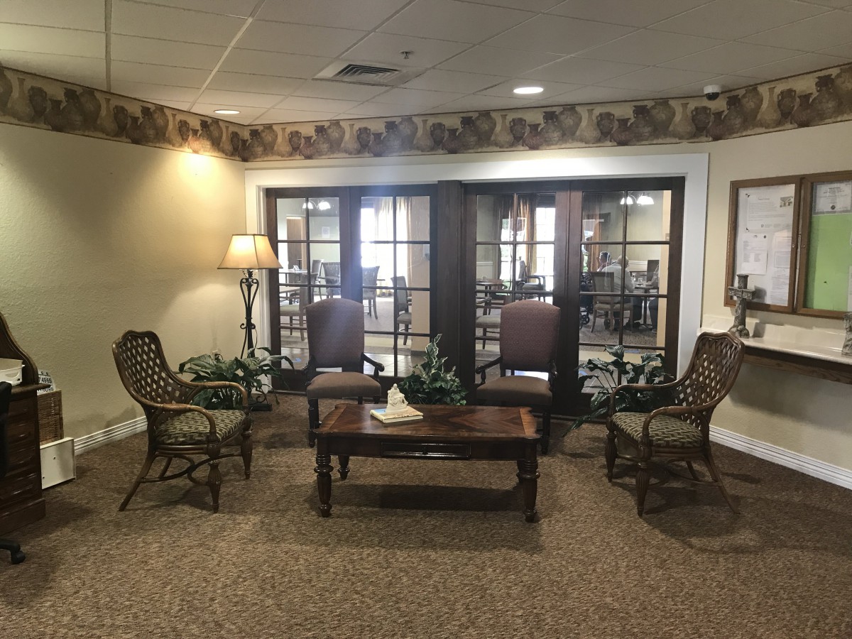 A cozy waiting area with comfortable chairs and a wooden table in a lobby setting.