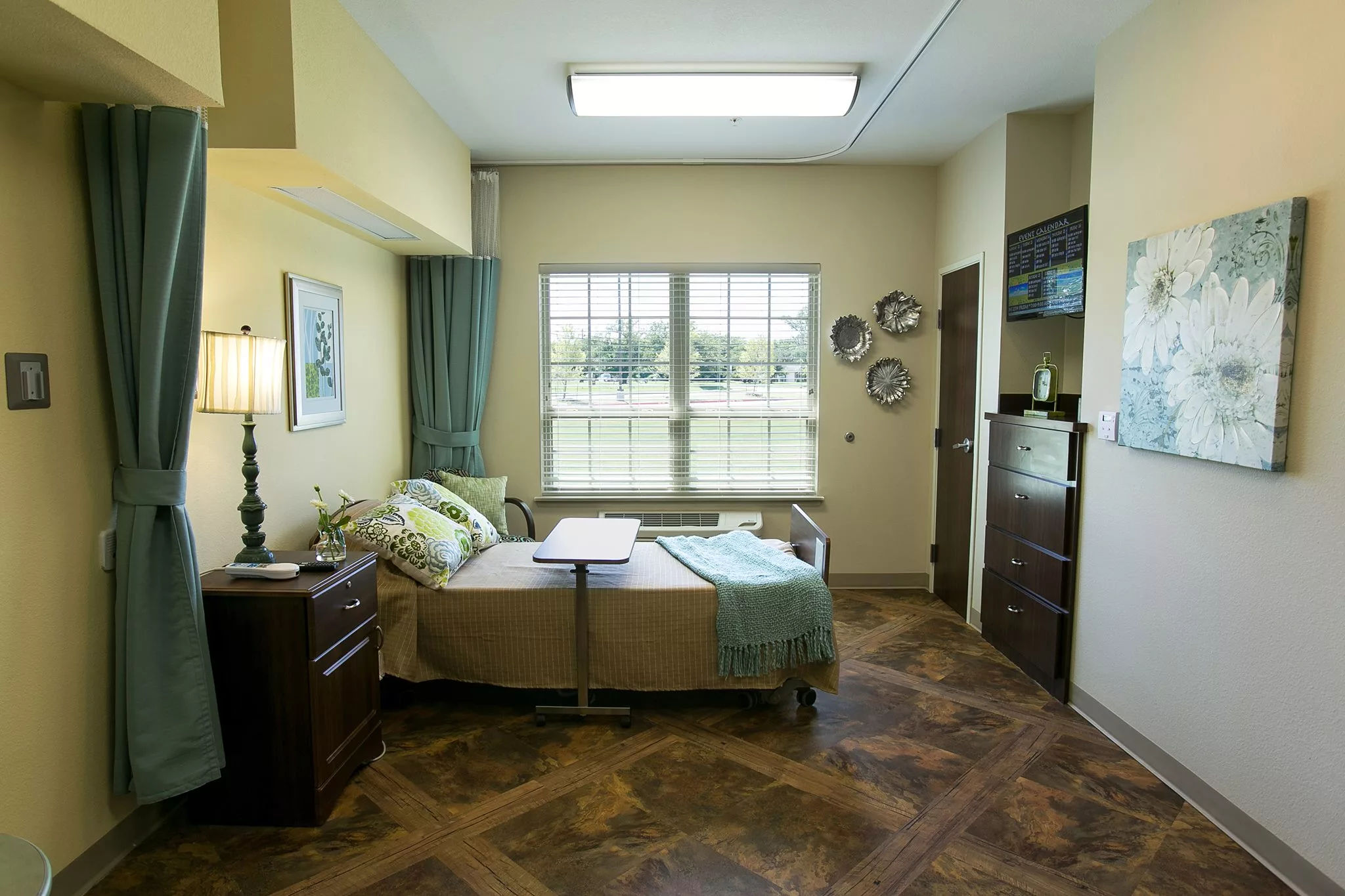 A well-decorated hospital room with a bed, window, and various furnishings.
