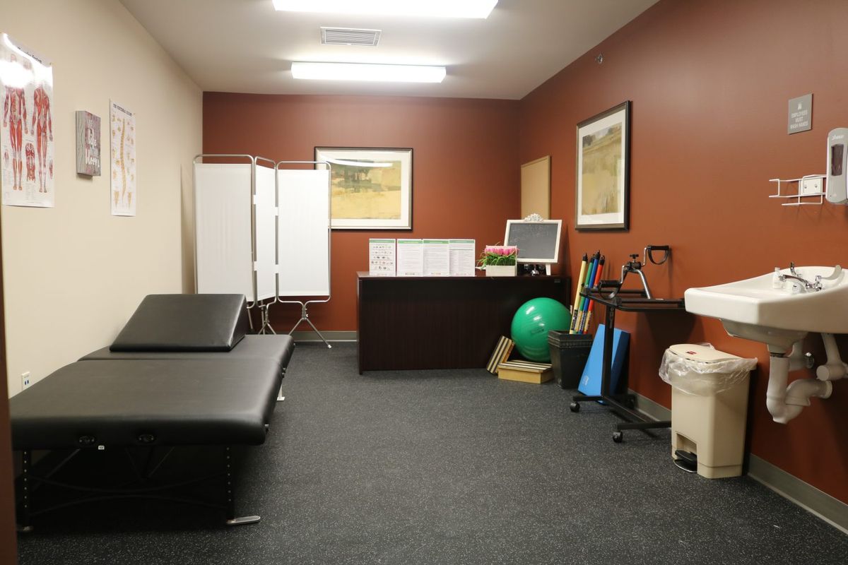 A physical therapy clinic room with a treatment table and exercise equipment.