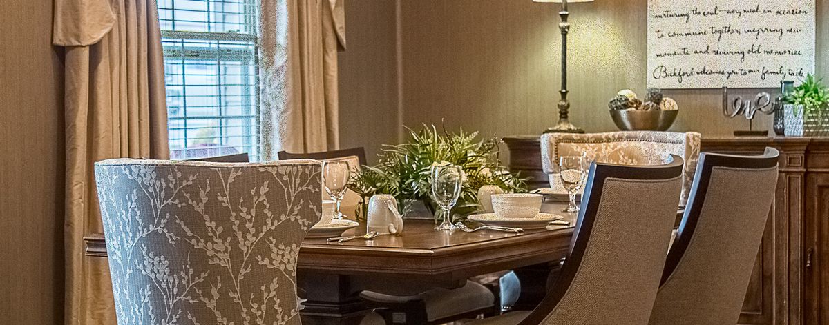 An elegantly set dining room table with a centerpiece of greenery.