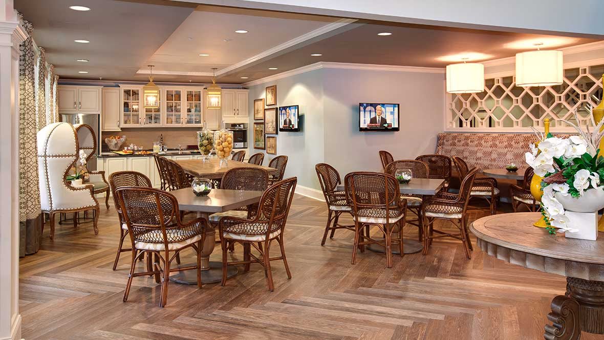 A modern restaurant interior featuring a dining area with tables and chairs, adjacent to an open kitchen.