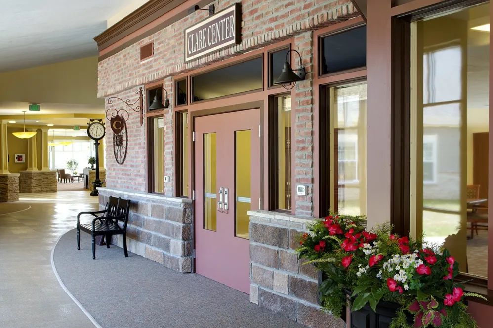 A charming storefront entrance adorned with flowers and a bench.