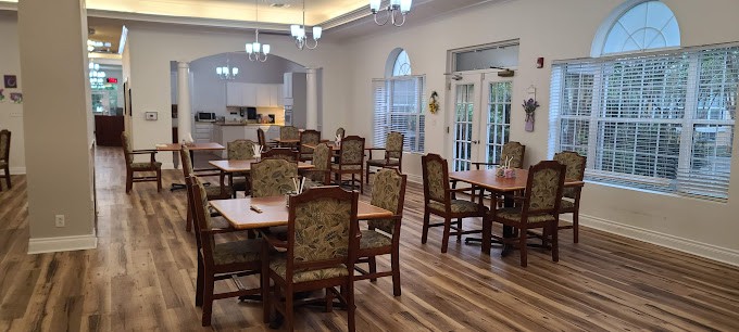 A spacious dining area with multiple tables and chairs, featuring wooden floors and elegant lighting.