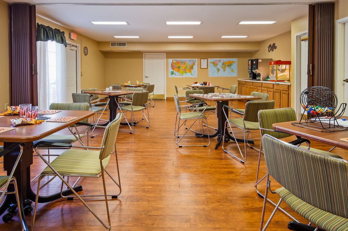 An empty dining area with neatly arranged tables and chairs, featuring maps on the wall.