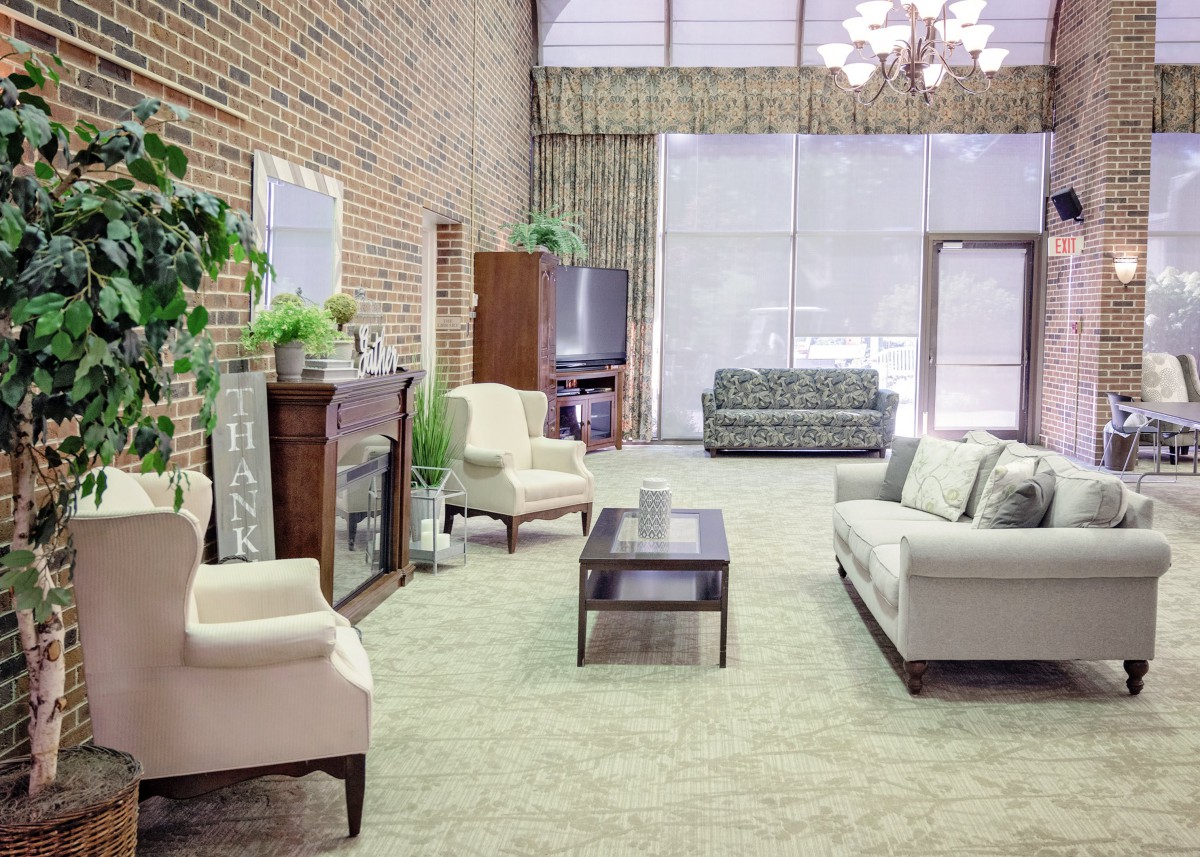 A spacious living room with modern furniture and a brick accent wall.