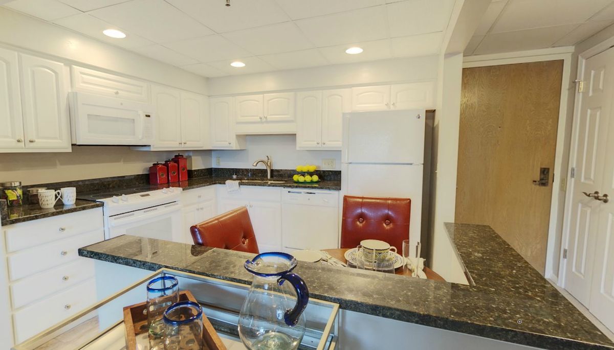 A modern kitchen with white cabinets and a dining area.