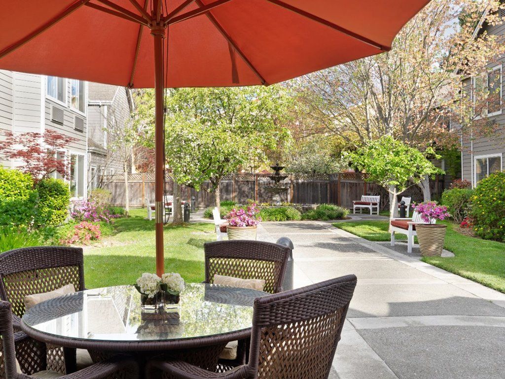 A peaceful patio area with a table, chairs, and an umbrella overlooking a garden.