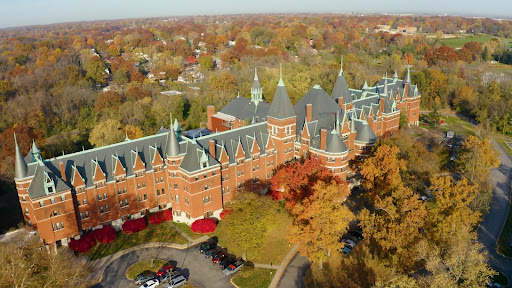 Aerial view of a historic university building surrounded by autumn foliage.