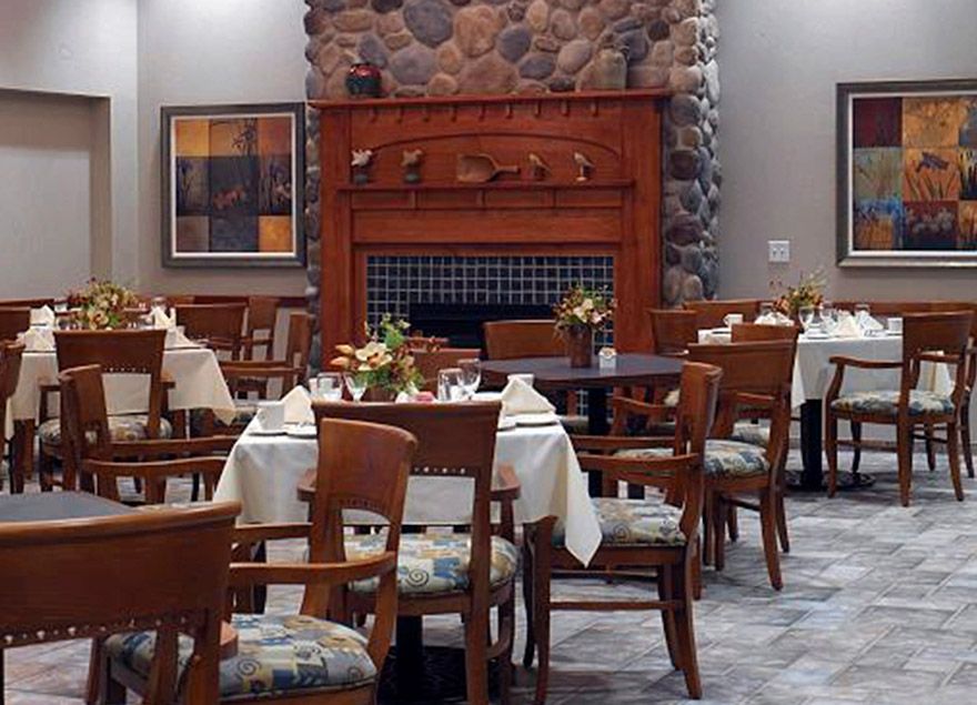 A cozy restaurant dining area with neatly arranged tables and a fireplace.