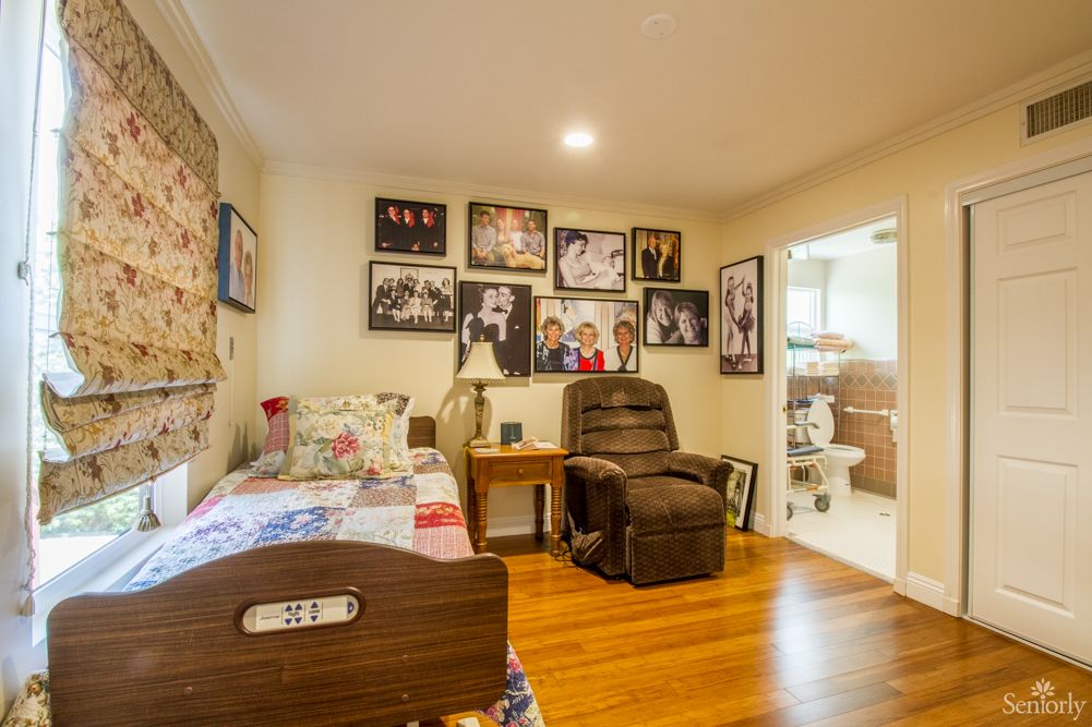 A cozy bedroom with a bed, recliner chair, and photographs adorning the walls.