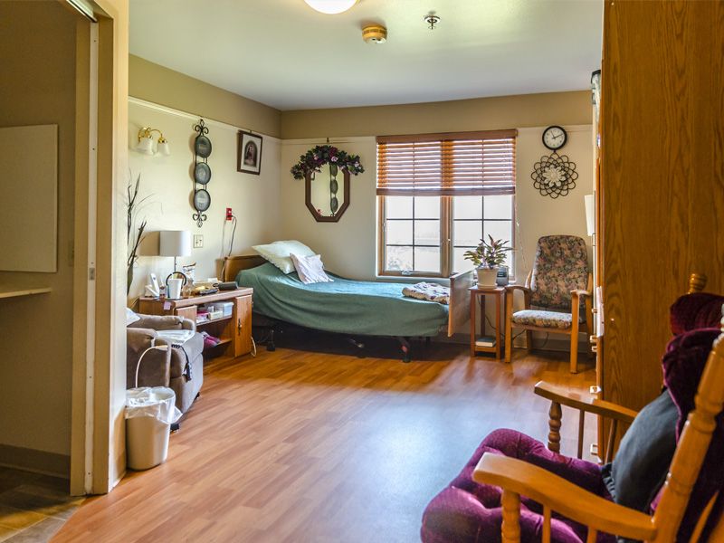 A cozy, well-decorated bedroom with a large window and wooden flooring.