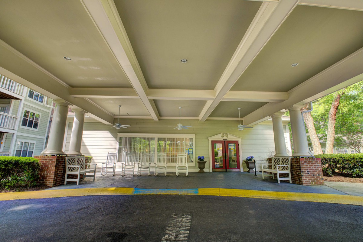 A covered entrance area of a building with columns and seating.