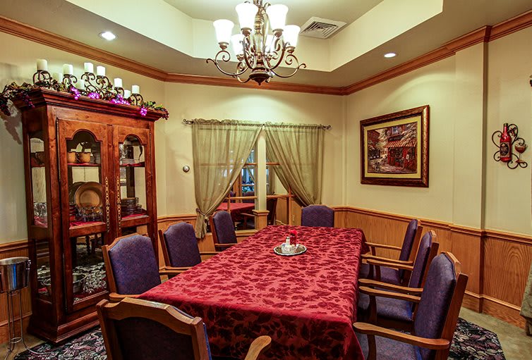 A warmly lit dining room with a red tablecloth and elegant decor.