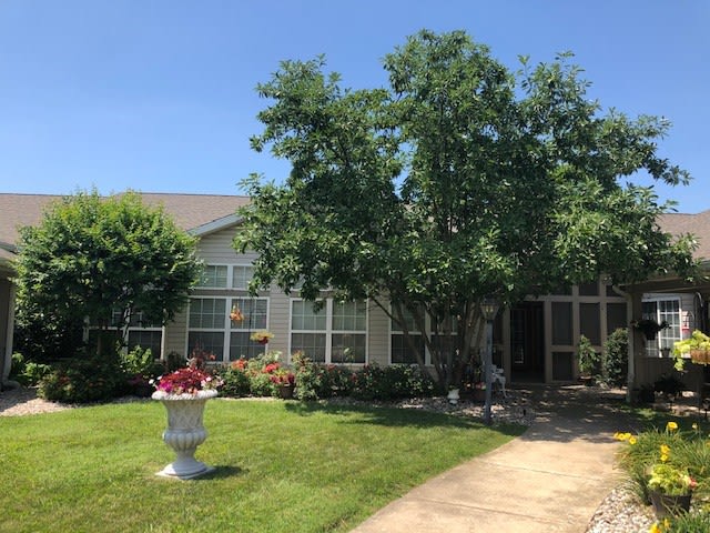 A suburban house with a well-maintained front yard featuring trees and a flower pot.