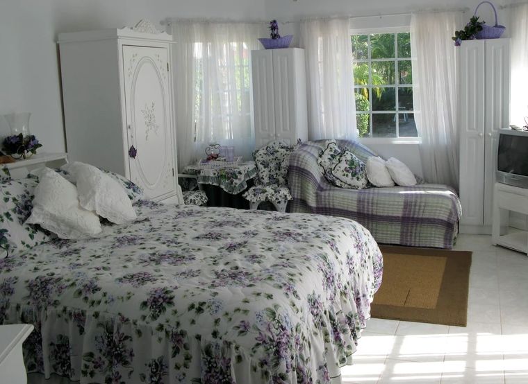 A cozy bedroom with floral patterned bedding and abundant natural light.