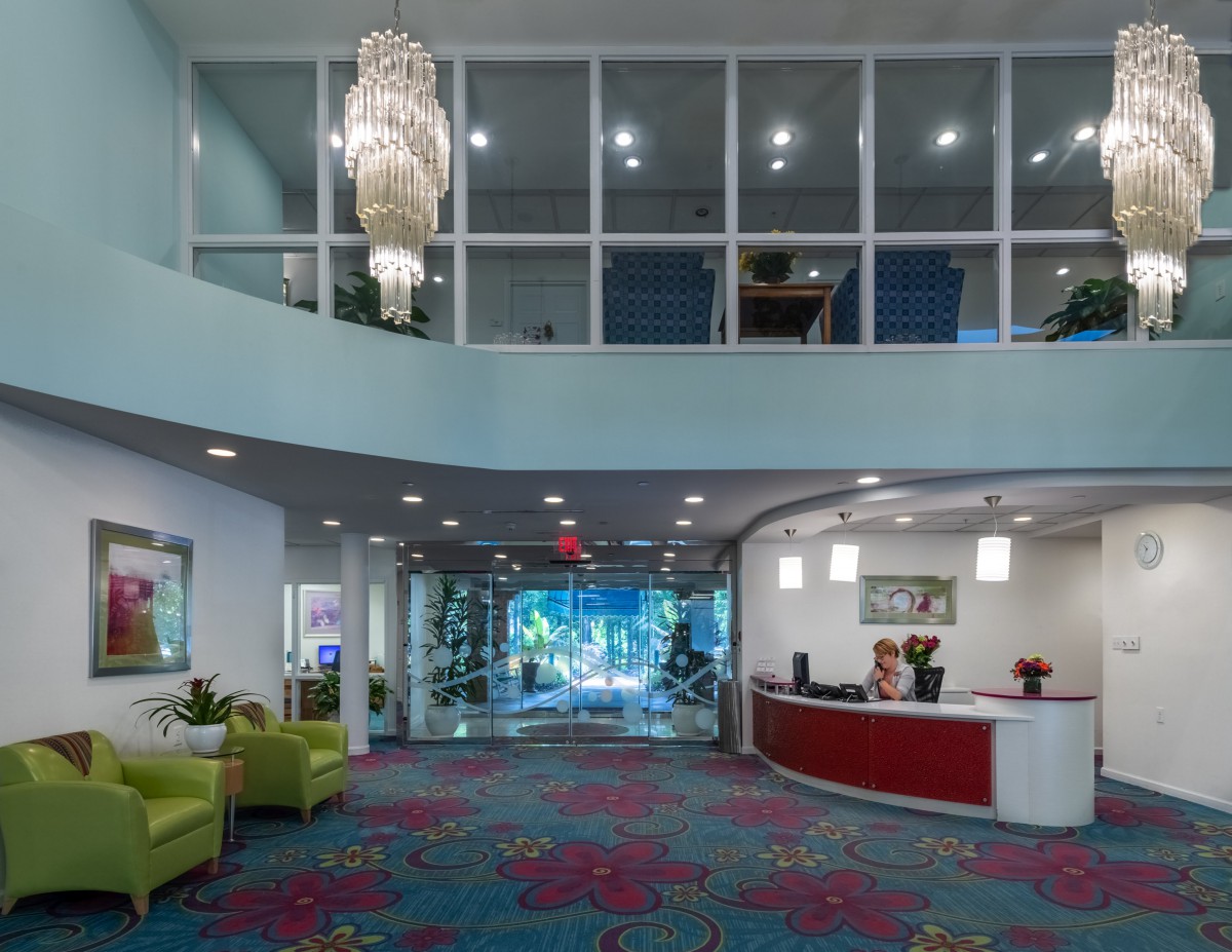 A modern lobby featuring a chandelier, reception desk, and seating area.