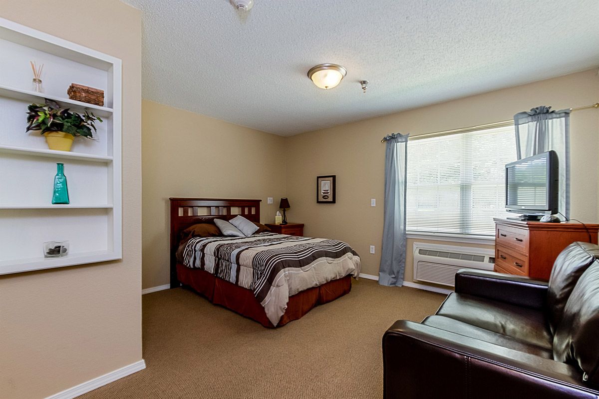 A cozy bedroom with a neatly made bed, soft lighting, and a large window.