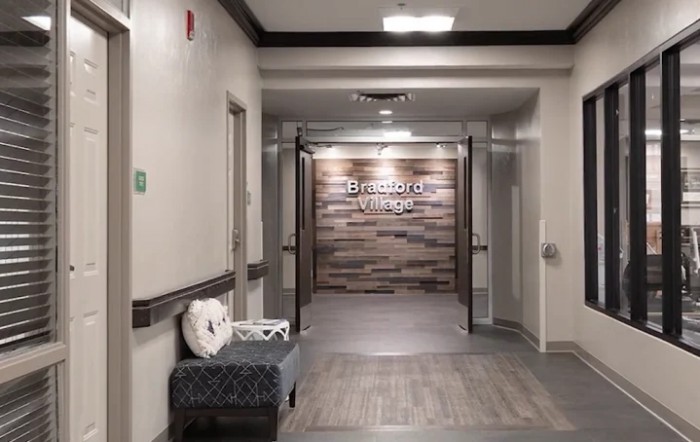 A clinic hallway with wood paneling and a bench.