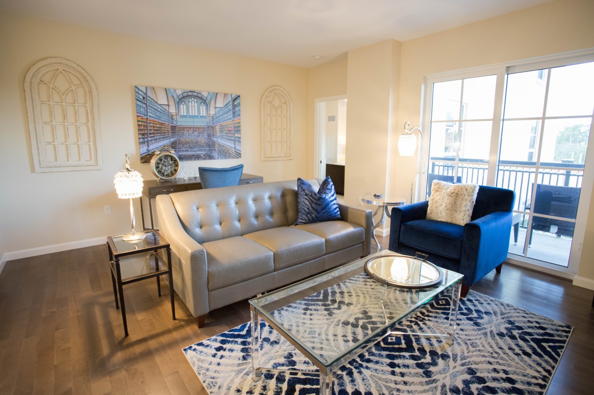 A stylish living room with a comfortable sofa, artwork on the wall, and a patterned rug.