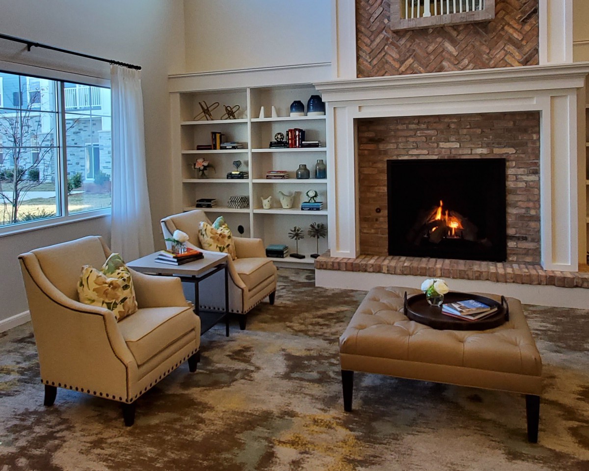 A cozy living room featuring a lit fireplace, comfortable armchairs, and a well-decorated bookshelf.