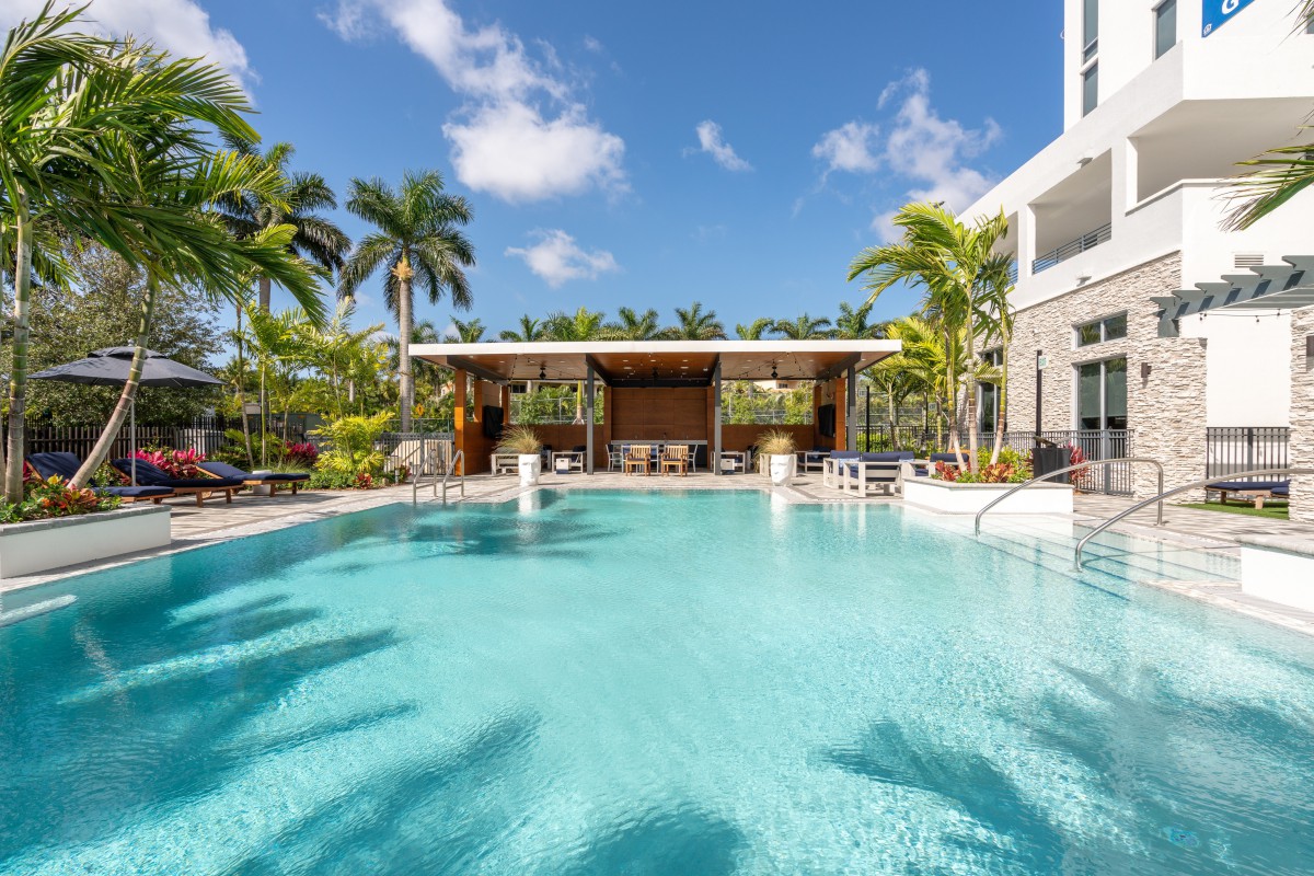 A luxurious outdoor swimming pool surrounded by palm trees at a tropical resort.