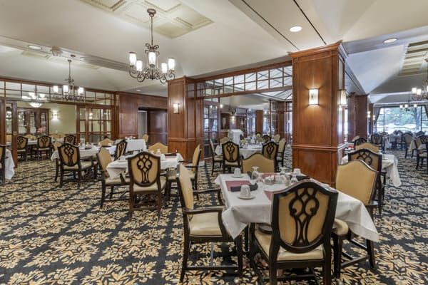 An elegant dining room with beautifully set tables and intricate chandeliers.