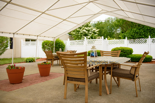 A cozy outdoor dining area set up under a large tent, perfect for gatherings and enjoying the garden view.