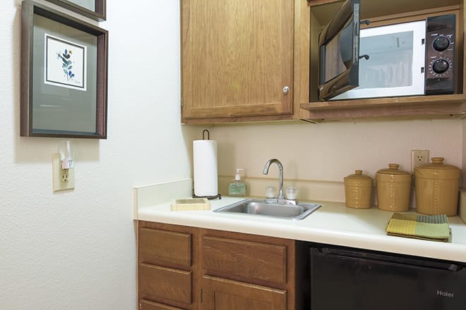 A small kitchen area with wooden cabinets, a sink, and a microwave.