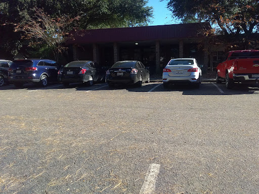 A view of a parking lot with several cars parked in front of a building on a sunny day.
