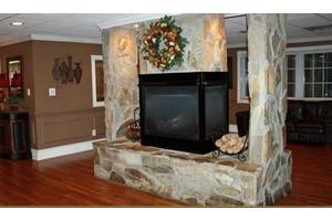 A stone fireplace in a cozy living room with a decorative wreath.