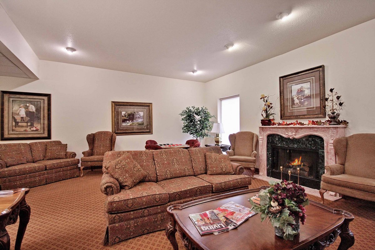 A cozy living room with a sofa, armchairs, and a fireplace.