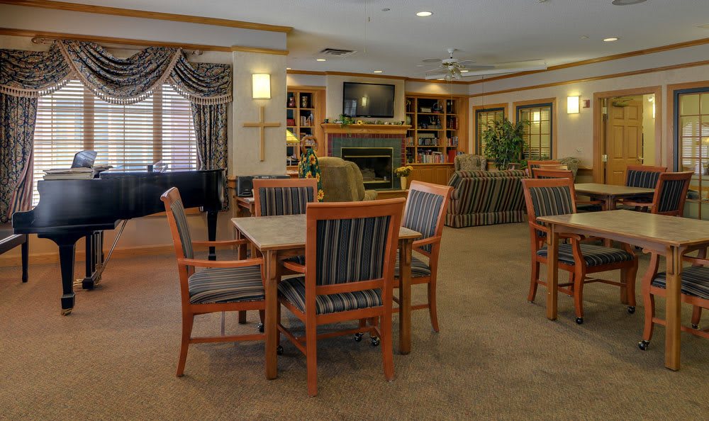 A cozy and elegantly furnished dining area with wooden chairs and tables, featuring a fireplace and television.
