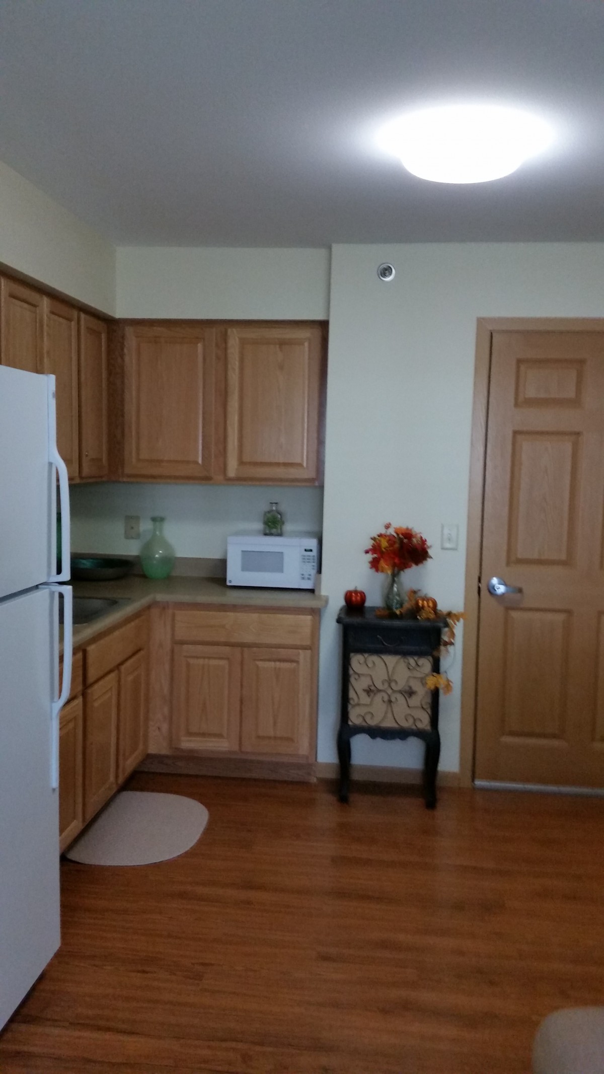 A cozy kitchen with wooden cabinets, a white refrigerator, and a microwave on the counter.