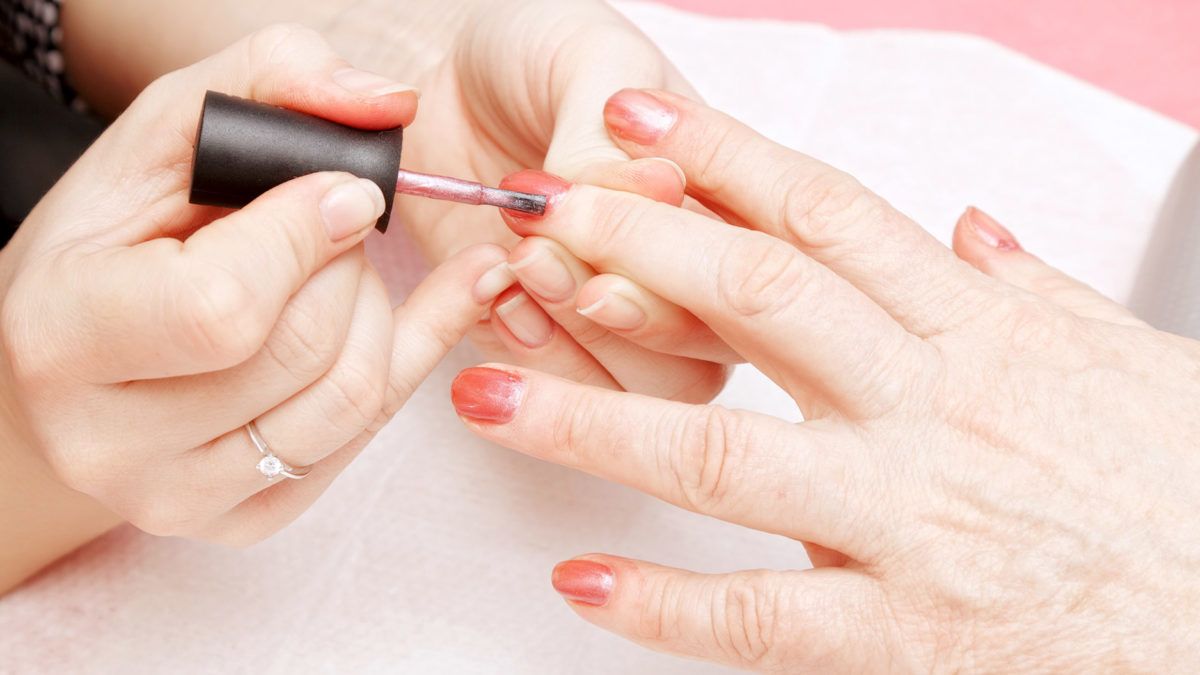 A person applying nail polish during a manicure session.