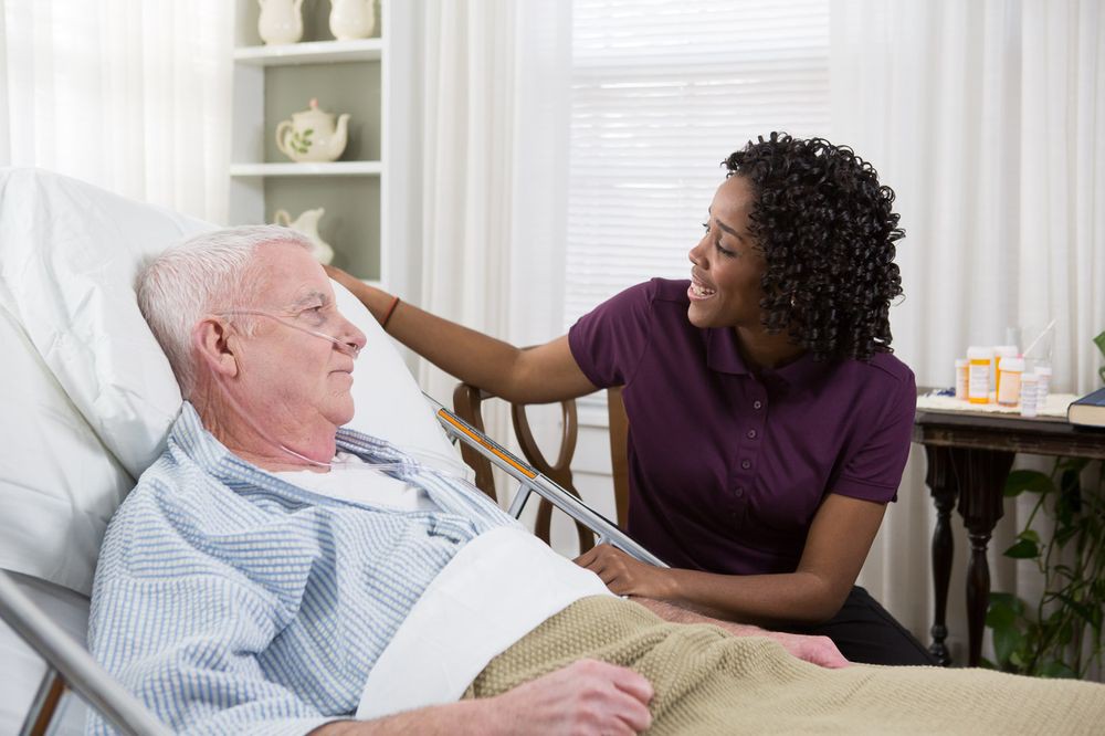 A caregiver attending to an elderly patient in a healthcare setting.