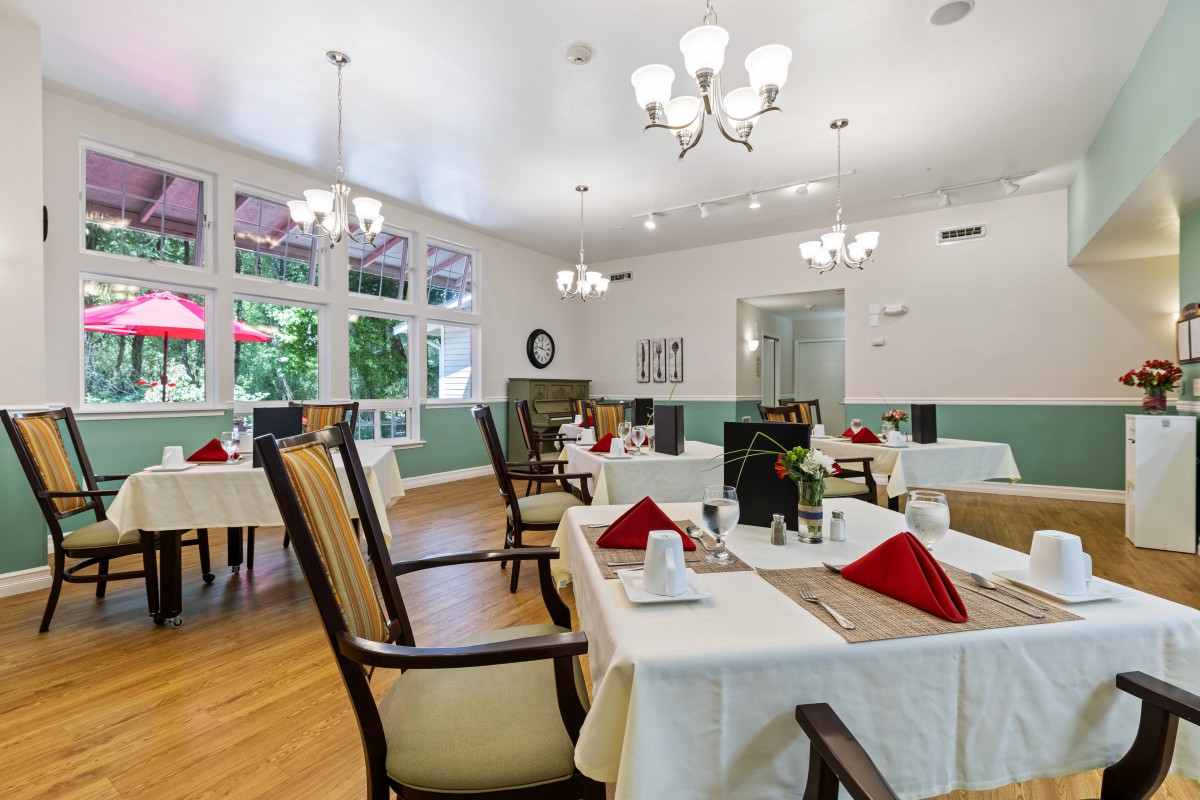 An elegant dining room set up with tables and chairs, featuring chic chandeliers and tasteful place settings.