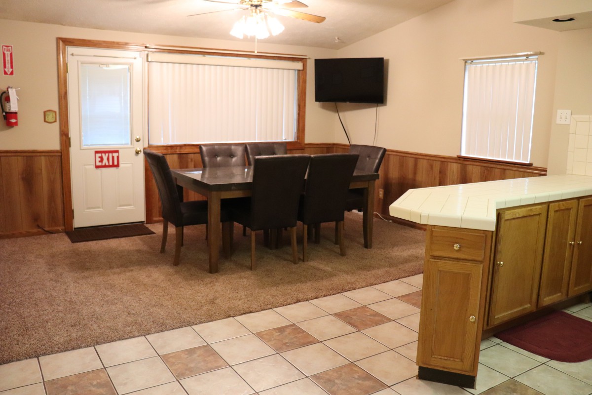 A cozy dining room with a table, chairs, and a wall-mounted television.