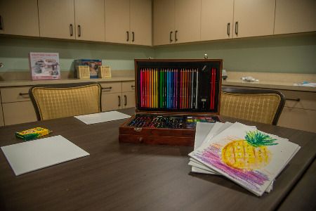 A set of colored pencils and a sketchbook on a table in an art room.